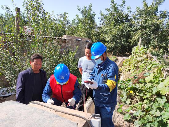 8月25日，国网温宿县供电公司员工巴吐尔·托合提和图尼亚孜·艾麦尔在温宿县柯柯牙镇园林村对抽水排灌设备进行用电检查。赵二安 摄