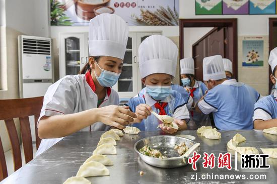 小学生在老师指导下学习包饺子。 陈月明（通讯员） 摄
