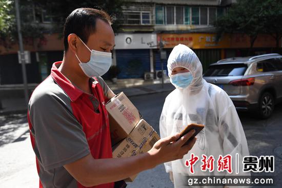 9月8日，在贵阳市南明辖区内的一小区楼栋疫情防控卡点，防疫人员正在检验配送员的“健康码”。