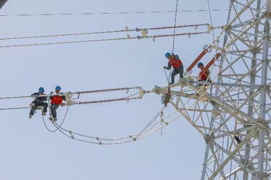 9月9日，在和田洛浦光伏试点示范项目220千伏送出工程作业现场，施工作业人员正在十几米的高空加紧施工作业。甄立民 摄