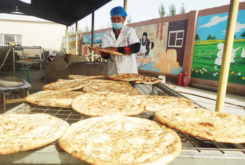 9月16日，阿克蘇普鄉卓源馕合作社打馕師傅尼亞孜汗·牙生在熟練地盤旋一張偌大的馕餅。唐雪芹攝
