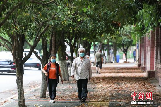 9月20日，贵阳市花溪区，市民佩戴口罩在街道散步。近两日，贵州省贵阳市实施分级分类疫情防控措施，有序恢复生产生活秩序。 瞿宏伦 摄