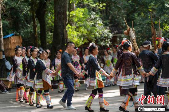 贵州省从江县丙妹镇岜沙苗寨景区，游客与村民一起跳芦笙团结舞。　吴德军 摄