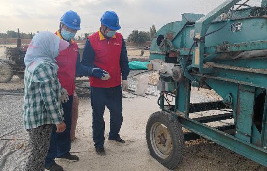 国网福海县供电公司员工向正在收葵花的农户宣传安全用电常识。乌兰 摄