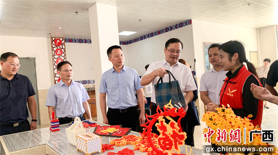 出席仪式的领导在基地参观残疾人制作的手工产品。冯俊铭 摄