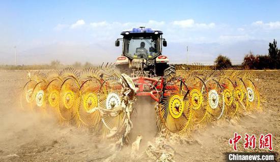 在新疆兵团第二师二十二团三连农田里，一辆牵引搂膜农机在地里来回穿梭，清除残留农膜。　李帆 摄