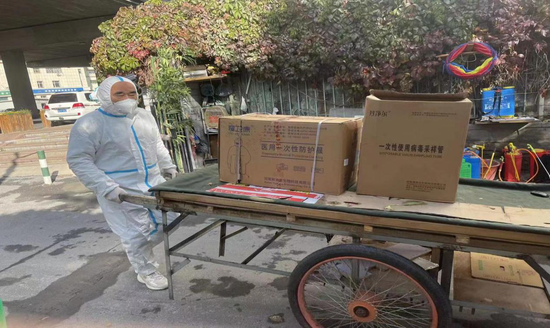 图为自治区联社办公室员工阿不都沙拉木·阿不都热合曼在搬运防疫物资。