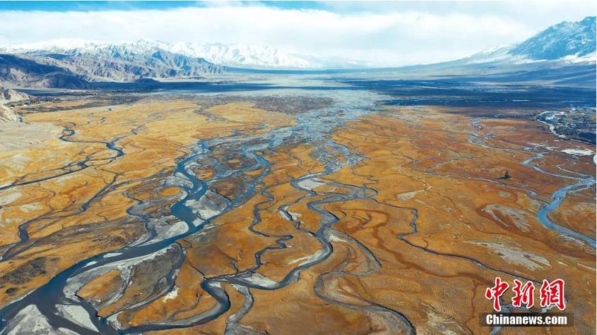 深秋季节，地处帕米尔高原上的新疆喀什地区塔什库尔干塔吉克自治县的草滩上泛着金黄，蜿蜒清澈的塔什库尔干河，远处的雪山和千年古城构成了一幅秋季画卷。图为新疆帕米尔高原上的塔什库尔干河流经阿拉尔金草滩清澈蜿蜒。 王红 摄