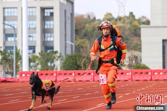 参赛训导员和搜救犬在进行“携犬负重跑”项目比赛。　瞿宏伦 摄