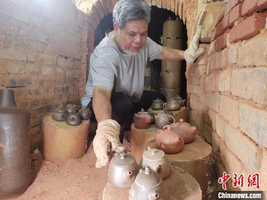 资料图：窑工师傅从古龙窑内拿出坭兴陶茶壶。　翟李强 摄