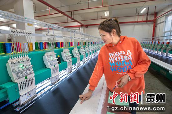 2022年11月23日，贵州省黔西市经济开发区（岔白园区）内一家苗族服饰加工车间，工人查看绣花机工作状态。