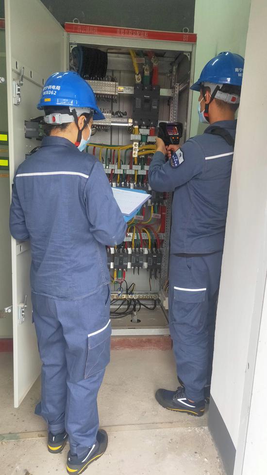南方电网广西南宁供电局工作人员正在测出线开关的温度。罗先彬 摄