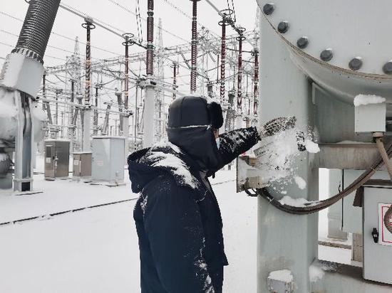 11月27日，国网新疆超高压分公司750千伏乌北变电站值班员清扫设备三箱计积雪。韩晓翔 摄