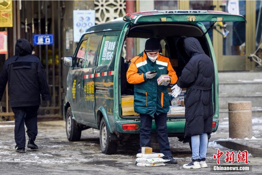 图为邮政快递员将车辆停靠在一小区门口，为居民提供快递领取服务。 刘新 摄