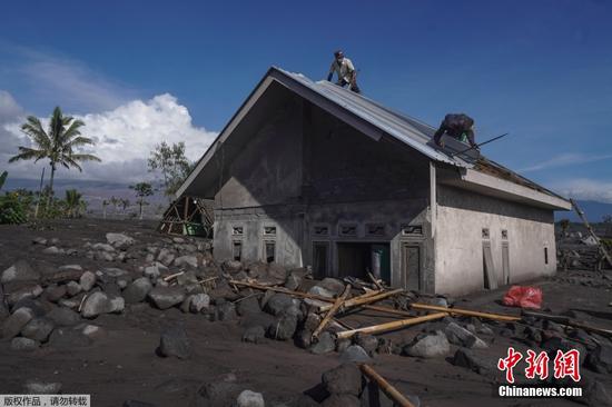 当地时间12月4日2时46分，位于印尼东爪哇省的塞梅鲁火山开始剧烈喷发。据印尼媒体报道，4日至5日，塞梅鲁火山已喷发22次，火山灰遮蔽了多个村庄。救灾部门设立11个临时安置点安置近2000名被迫离开家园的当地民众。图为当地时间12月6日，印尼东爪哇省Sumberwuluh村居民清理被火山灰覆盖的房屋。