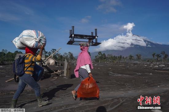 当地时间12月4日2时46分，位于印尼东爪哇省的塞梅鲁火山开始剧烈喷发。据印尼媒体报道，4日至5日，塞梅鲁火山已喷发22次，火山灰遮蔽了多个村庄。救灾部门设立11个临时安置点安置近2000名被迫离开家园的当地民众。图为当地时间12月6日，印尼东爪哇省Sumberwuluh村居民携带家中物品撤离。