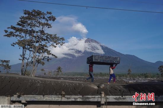 当地时间12月4日2时46分，位于印尼东爪哇省的塞梅鲁火山开始剧烈喷发。据印尼媒体报道，4日至5日，塞梅鲁火山已喷发22次，火山灰遮蔽了多个村庄。救灾部门设立11个临时安置点安置近2000名被迫离开家园的当地民众。图为当地时间12月6日，印尼东爪哇省Sumberwuluh村居民扛着床垫撤离。
