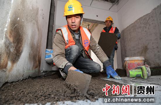 12月12日，在贵阳市南明区南明智能制造产业园三期项目建设现场，中铁八局集团第三工程有限公司的工人正在铺贴地砖。