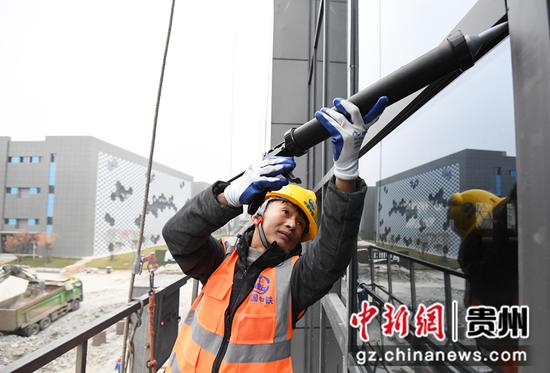 12月12日，在贵阳市南明区南明智能制造产业园三期项目建设现场，中铁八局集团第三工程有限公司的工人正在进行打玻璃密封胶作业。