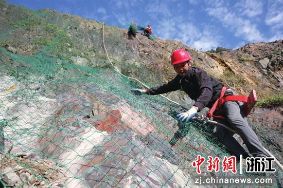 工人在陡坡上小心地铺设护坡网。吴建勋 摄