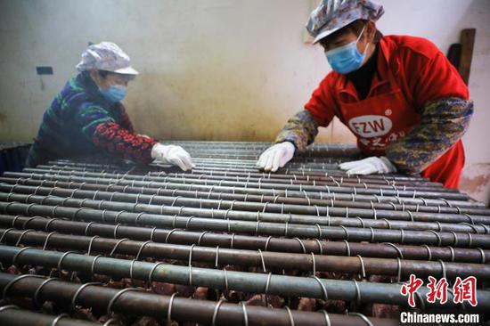 工人在贵州省江口县一家旅游食品加工作坊烘烤牛干巴。　李鹤 摄