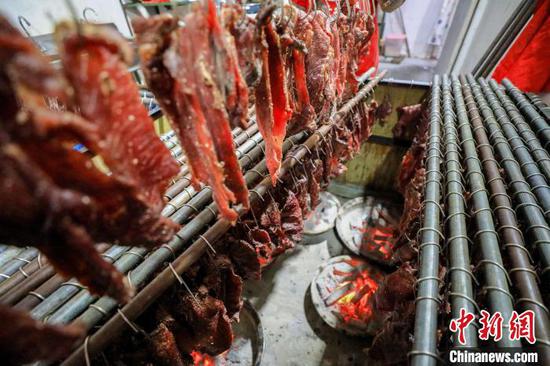 贵州省江口县一家旅游食品加工作坊，正在用炭火烘烤牛肉制作牛干巴。　李鹤 摄