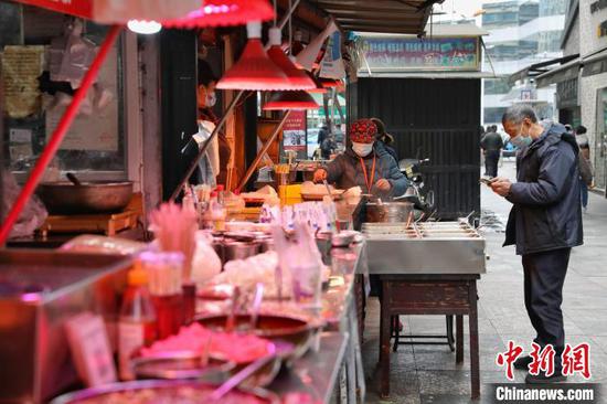 12月6日，市民在贵阳市南横街购买美食。　瞿宏伦 摄
