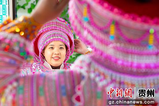 2022年12月14日，贵州省黔西市红林彝族苗族乡鱼塘村一家苗族服饰加工车间，村民试穿刚加工好的苗族服饰。