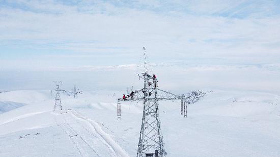 12月10日，在零下20℃的山区，国网伊犁伊河供电公司员工在220千伏温巩线19号塔进行组塔抢修工作。（拜新成 摄）
