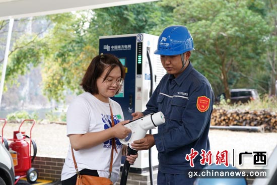 南方电网广西桂林阳朔供电局工作人员为游客介绍充电桩的正确使用。陆国辉摄