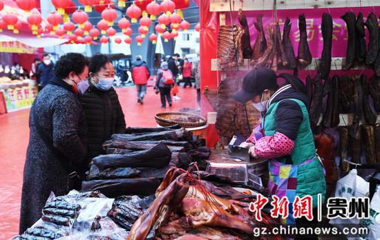 12月31日，市民在贵阳市南明区2023幸福中国-贵阳第八届迎春年货节集市选购腊味食品。