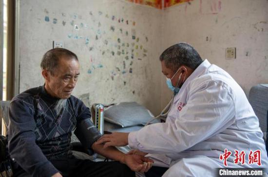 在从江县翠里瑶族壮族乡高文村，村卫生员文齐华（右）给75岁的老人测量血压。　吴德军　摄