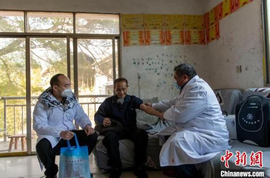 在从江县翠里瑶族壮族乡高文村，村卫生员文齐华(右)给75岁的老人测量血压。　吴德军 摄