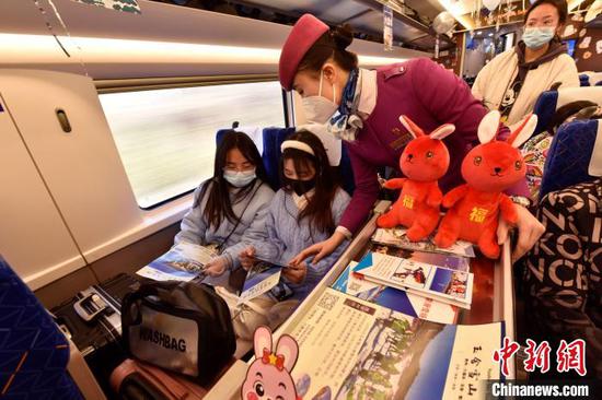 “冰雪主题”列车上，乘务员向旅客介绍情况。　黄春海 摄