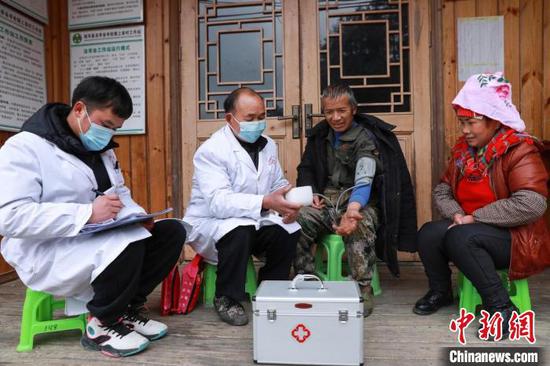 剑河县岑松镇上岩寨村，邰秀武（左二）与邰剑给村民测量血压。　刘梦　摄