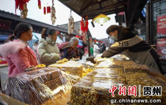 游客在贵州省黔东南苗族侗族自治州丹寨县万达小镇景区选购小吃。