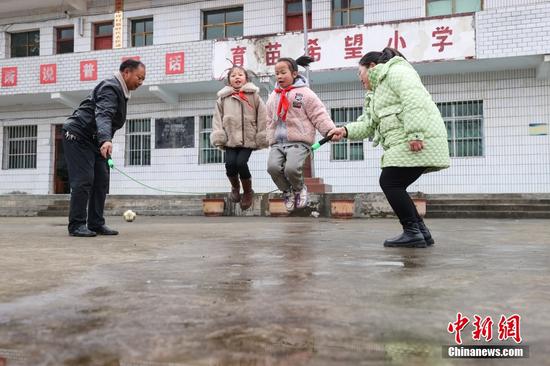 2月15日，杨朝俊（左）和青年教师吉庆华在中午休息时协助学生跳绳。