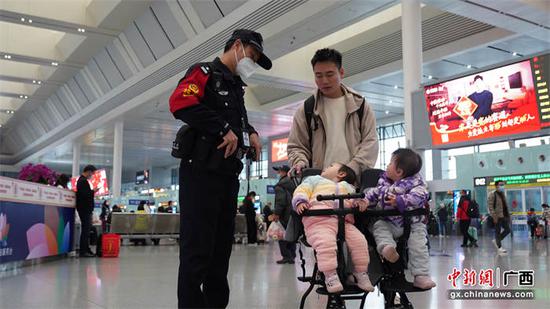 高明伟向陪同双胞胎出行的旅客讲解便捷出行措施。 符振华摄 高明伟向陪同双胞胎出行的旅客讲解便捷出行措施。 符振华摄