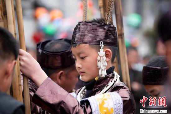 在贵州从江县停洞镇领袜村，一名苗族男孩在“燕子节”帮助大人掌大芦笙。　吴德军 摄