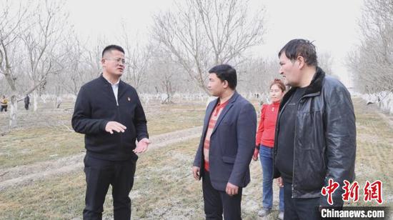 图为逄子剑(左一)在麦田和群众交谈。