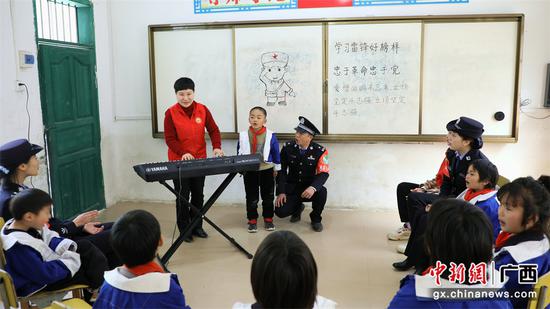 图为民警和志愿者在教孩子们唱《学习雷锋好榜样》歌曲。甘勇 摄（2）