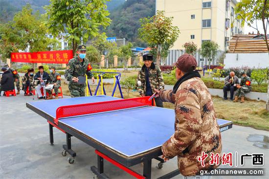 武警官兵与老人打乒乓球。