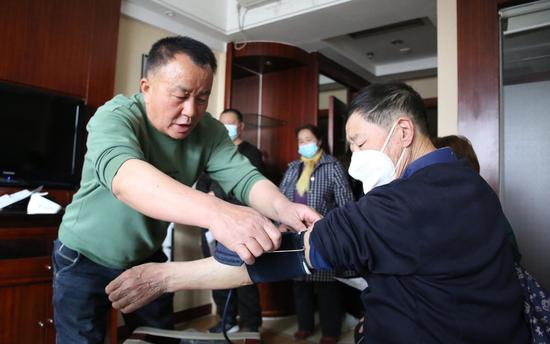若羌县委老干部局干部帮助退休老干部测量血压。