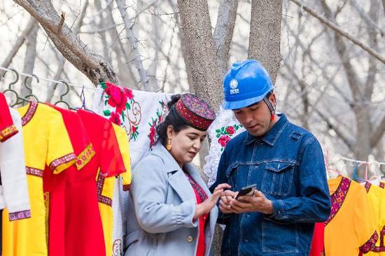 在塔尔塔吉克族乡供电员工帮助当地用电客户使用网上国网App。周广科 摄