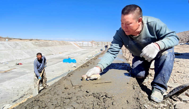 4月4日，在新疆伊犁哈萨克自治州察布查尔锡伯自治县加尕斯台镇高标准农田建设施工现场，施工人员在沉砂池边磨平混泥土。华岩明摄 