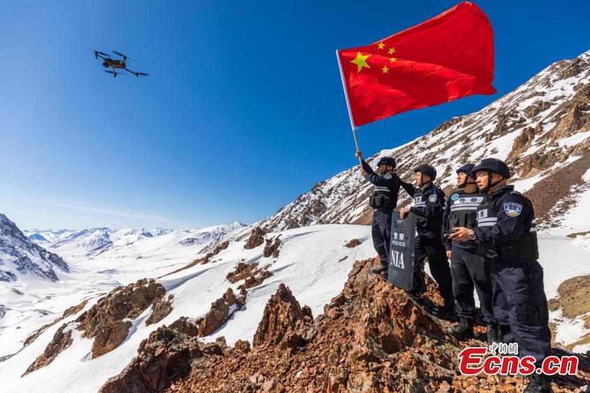 Police officers walk hand-in-hand on a snow-covered mountain to patrol the border area more than 3,600 above sea level in northwest China's Xinjiang Uyghur Autonomous Region, April 9, 2023. (Photo: China News Service/Lv Zhiheng)

