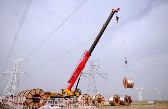 4月7日，在独山子大峡谷，伊犁—博州—乌苏—凤凰Ⅱ回750千伏输变电工程张力场作业人员正在调运设备。（马元 摄）
