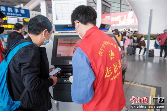 南宁机场志愿者协助旅客使用自助值机设备。南宁机场供图