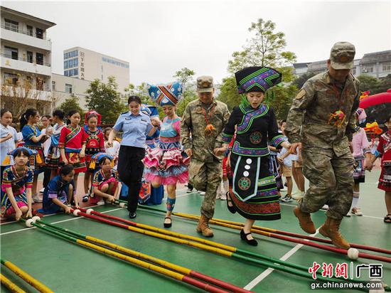 图为友谊关边检站移民管理警察与少数民族边民及驻地部队一起跳壮族竹竿舞。王皓东  摄