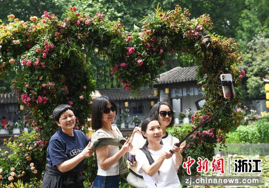 游客在心形月季花装置前自拍合影。  王刚 摄